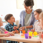 Young woman playing with little children indoors