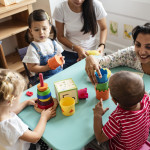 Nursery children playing with teacher in the classroom