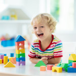 Kids toys. Child building tower of toy blocks.