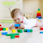 Cute baby girl playing with colorful rattle toys