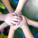 Top view of high five kids hand gesture in junior football team.Boy standing in circle with stack of hands together showing unity.Symbol of celebration or greeting,Success and teamwork Concept.