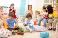 Kindergarten teacher with children on music lesson in daycare. Little kids toddlers play together with musical toys.
