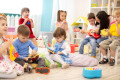 Kindergarten teacher with children on music lesson in daycare. Little kids toddlers play together with musical toys.