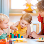Group of children and teacher playing in kindergarten