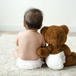 Back of a baby with a teddy bear