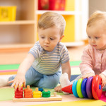Preschool boy and girl playing on floor with educational toys. Children at home or daycare.